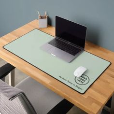 a laptop computer sitting on top of a wooden desk next to a white mouse pad