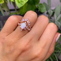 a woman's hand holding an opal and diamond ring