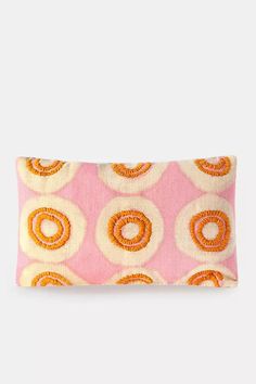 a pink and orange pillow with circles on the front, sitting on a white surface