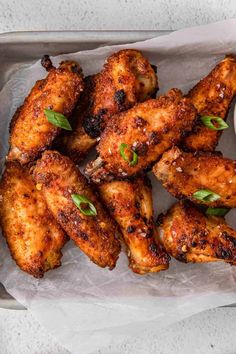 chicken wings in a tray with dipping sauce on the side and garnished with green leaves