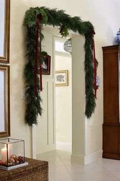 a hallway decorated for christmas with greenery and decorations on the door frame, along with a candle