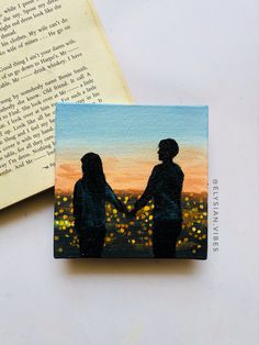 two people are holding hands in front of an open book with the sun setting behind them