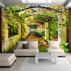 a living room filled with white furniture and walls covered in green trees, bushes and flowers