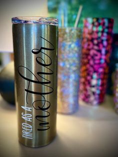 a stainless steel tumbler sitting on top of a table next to other cups and confetti