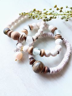 Soft, serene, cozy, and beachy. Beautiful beige, white, caramel, brown, and ecru in these mixed medium stack bracelets. Several white Howlite gemstone beads in different sizes and colors. Large ethical bone beads, matte sea shells dyed in a beige-gray, white and natural coconut disk beads, rustic antique beads, and African recycled glass. Mix in with an array of mixed metals, and cluster accents of mixed gemstone beads including pearls. Unique and stunning. The item/s pictured is the item you wi White Stackable Beaded Bracelets For Healing, Bohemian White Bracelets For Everyday, White Bohemian Stackable Bracelets, Bohemian White Stackable Bracelets, Bohemian White Beaded Bracelets With Natural Stones, White Bohemian Beaded Bracelets For Healing, Stretch Beaded Bracelets Diy, Bracelet Trio, Stack Bracelets