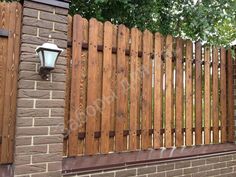 a brick wall with a wooden fence and street light on the side, in front of a tree