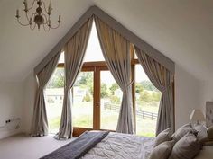 a large bed sitting in the middle of a bedroom next to a window with curtains on it