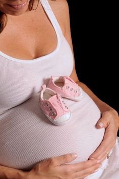 a pregnant woman wearing pink shoes and holding her stomach with the word, i love you on it