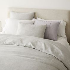 a bed with white linens and pillows on it