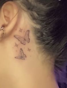 a woman with a butterfly tattoo on her left side behind the ear is looking down