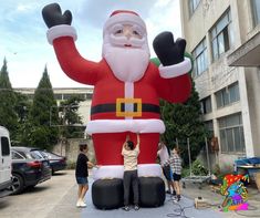 large inflatable santa clause sitting on top of a table with people standing around