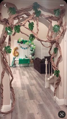 a living room decorated with balloons and greenery on the walls, as well as an arch made out of branches