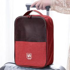 a person pulling a piece of luggage on top of a metal suitcase with red and black panels