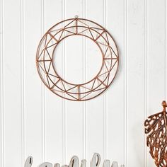 a metal sign that says welcome hanging on the wall next to a wire wreath with leaves