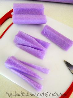 purple sponges are cut up on a cutting board with a pair of scissors next to them