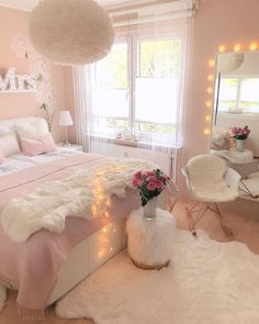 a bedroom decorated in pink and white with lights on the ceiling, fur rugs