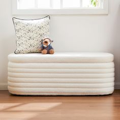 a stuffed animal sitting on top of an inflatable mattress next to a window