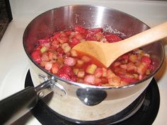 a pot filled with food sitting on top of a stove next to a wooden spoon