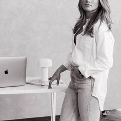 black and white photograph of a woman leaning on a desk with an apple computer in front of her