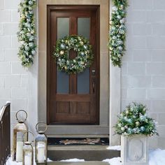 the front door is decorated with wreaths and lanterns