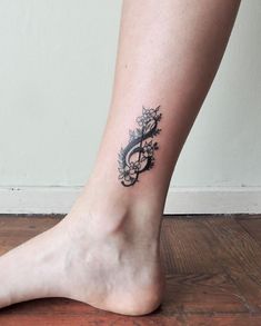 a woman's foot with a tattoo design on the side of her leg, which is decorated with vines and flowers