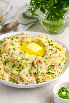 a white plate topped with an egg and ham casserole next to two bowls of greens