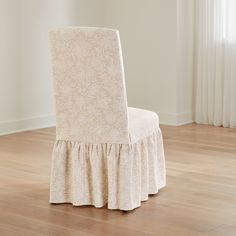 a white chair with a ruffled skirt on it's back in front of a window