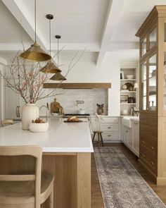 a kitchen with white counter tops and wooden cabinets next to a dining room table filled with chairs