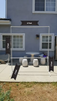 an outdoor table and chairs set up in front of a blue house with black signs