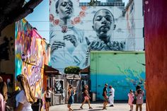 many people are walking down the street in front of graffiti