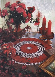 a table topped with red flowers and candles