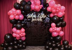 a black and pink balloon arch with lots of balloons