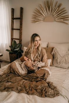 a woman sitting on top of a bed under a blanket