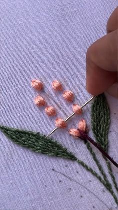 someone is stitching flowers on a piece of fabric with pins and needles to make them look like they have been made from yarn