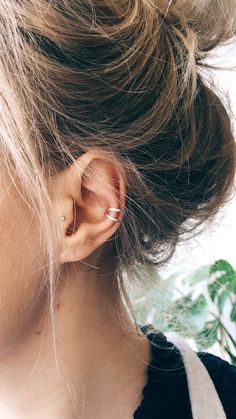 a close up of a person with ear piercings on their ears and behind them is a plant