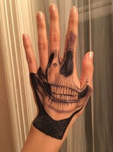 a person's hand with a skull tattooed on it