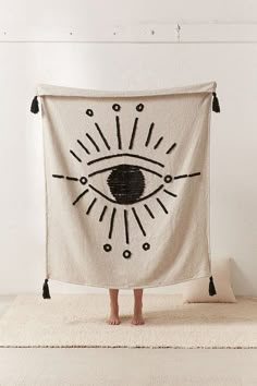 a person standing in front of a white wall holding a towel with an eye drawn on it