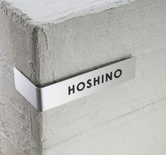 a sign that reads hoshino on the side of a cement block with a metal hook