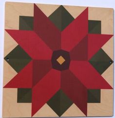 a red and green flower is on a wooden block with two squares in the middle