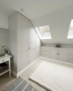 an attic bedroom with white cabinets and carpeted flooring, two windows above the closet