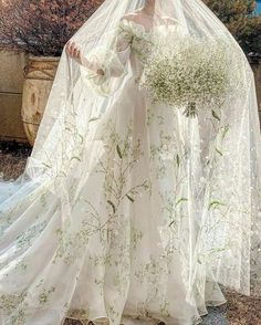 a woman in a white wedding dress with flowers on her head and veil over her face