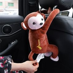 a stuffed monkey hanging from the side of a car seat in someone's hand