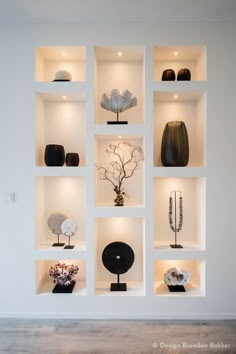 an arrangement of vases and other decorative items on shelves in a white walled room