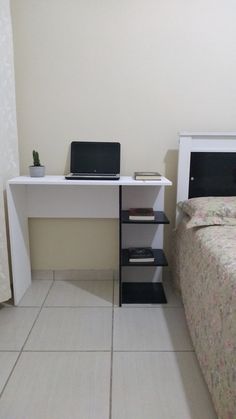 a bedroom with a bed, desk and laptop computer on the nightstand next to it