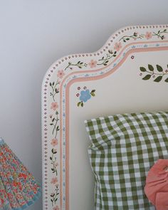 a white headboard with flowers and leaves on it next to a pink stuffed animal