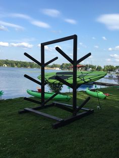 there is a sculpture made out of surfboards on the grass by the water's edge