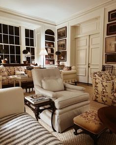 a living room filled with lots of furniture next to large window covered in framed pictures