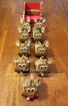 a group of reindeer made out of toilet paper on top of a wooden floor next to a red box