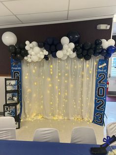 balloons and streamers decorate the backdrop for a graduation party in blue, white and black