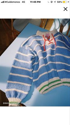 a blue and white striped sweater sitting on top of a table next to a wooden chair